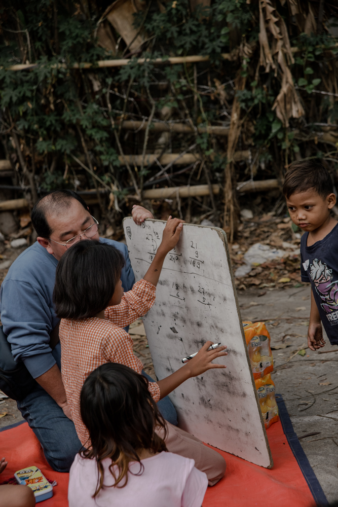 A volunteer tutoring children outdoors